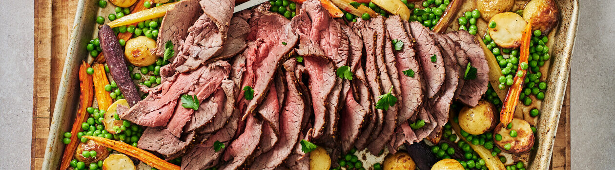 Honey-balsamic beef roast with vegetables on a sheet pan.